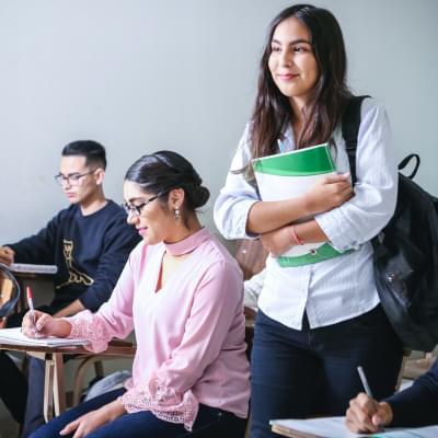 Femme portant un manuel scolaire blanc et vert